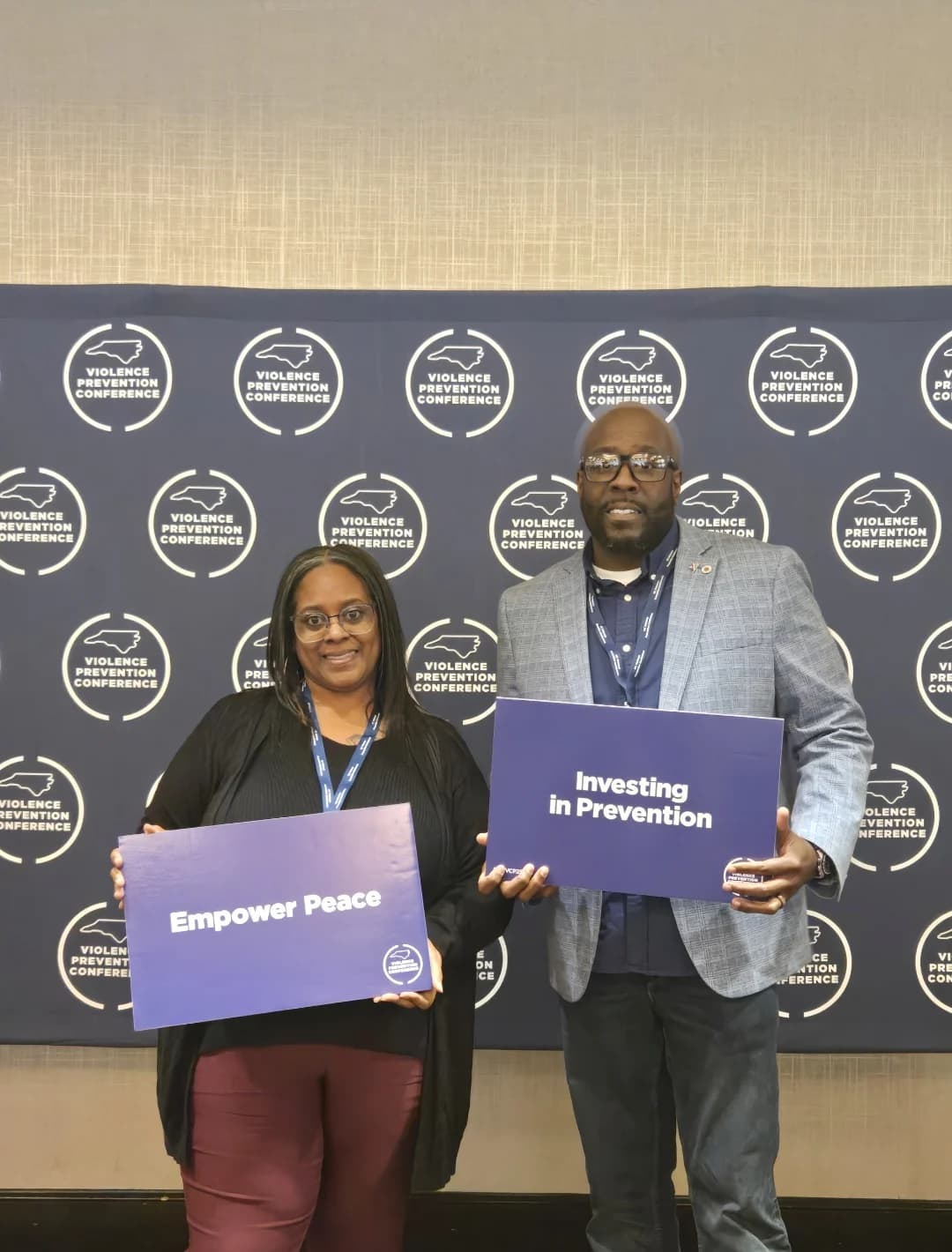 CJ Turrentine and a community partner holding Empower Peace and Investing in Prevention signs